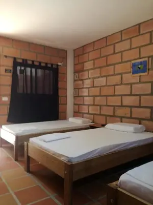 two beds in a room with a brick wall at Hotel Pizzeria Opera Tolú in Tolú