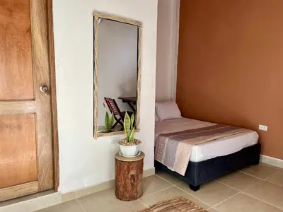 a small bedroom with a bed and a mirror at Isla Rosa Coveñas - Alojamiento in Coveñitas