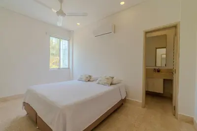a white bedroom with a bed and a mirror at Casa Areia Frente Al Mar, Playa Privada in Playa Blanca