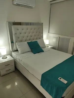 a bedroom with a large white bed with a green blanket at Cozy 2nd Floor Apartment in Heart of Cartagena in Cartagena de Indias
