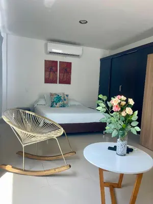 a room with a bed and a table with a vase of flowers at Apartamento 201 frente a hotel Las américas in Cartagena de Indias