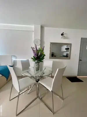 a glass table with white chairs and a vase with flowers at Cielo mar 202 frente a hotel Las Américas in Cartagena de Indias