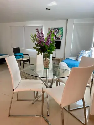 a glass table with white chairs and a vase of flowers at Cielo mar 202 frente a hotel Las Américas in Cartagena de Indias