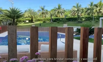 a fence in front of a swimming pool with palm trees at Resort frente al mar in Juan de Acosta