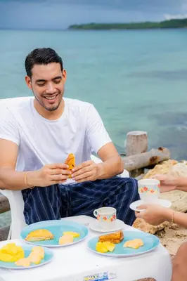 a man sitting at a table with plates of food at Mar Barú Beach House in Playa Blanca