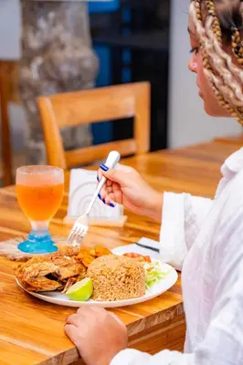 a woman sitting at a table with a plate of food at Mar Barú Beach House in Playa Blanca