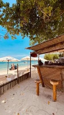 a table and benches on a beach with umbrellas at Rocha Beach Club in Playa Blanca