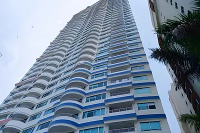 a tall building with blue windows and a palm tree at Increíble vista al mar en el corazón de Bocagrande in Cartagena de Indias