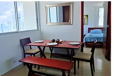 a dining room with a table and chairs and a bed at Increíble vista al mar en el corazón de Bocagrande in Cartagena de Indias