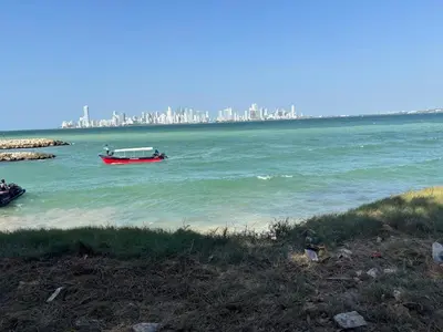 a red boat in the water with a city in the background at Villa del Atardecer Caribeño - JhonLimar in Bocachica