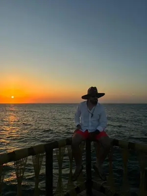 a man sitting on a fence watching the sunset at Villa del Atardecer Caribeño - JhonLimar in Bocachica