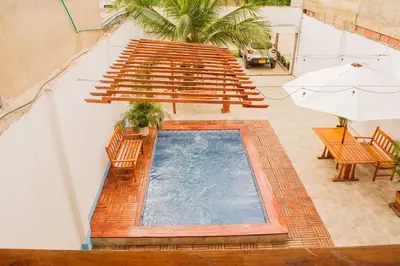 an indoor swimming pool with benches and an umbrella at Hb-m8 House With 8 Bedrooms, Pool And Near The Sea in Cartagena de Indias