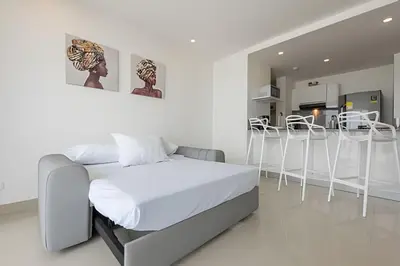 a white bedroom with a bed and a kitchen at 1004 Morros City - Spectacular 1 Bedroom Condo in Cartagena de Indias