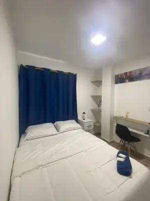 a bedroom with a bed with a blue curtain and a desk at Hotel Boutique DL in Cartagena de Indias
