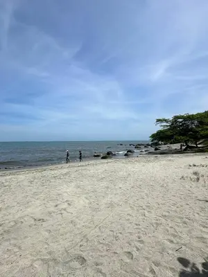 two people walking on a sandy beach near the ocean at Apartasuite x4 Playa Piscina Jacuzzi Zona Decameron Santa Marta in Santa Marta