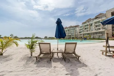 a table with a blue umbrella and two chairs on the beach at Ubicación soñada en Cartagena | Apartamento premium en Baia Kristal in Cartagena de Indias