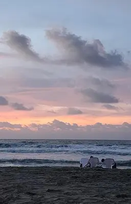 two beach chairs sitting on the beach at sunset at Mango Beach in San Bernardo del Viento
