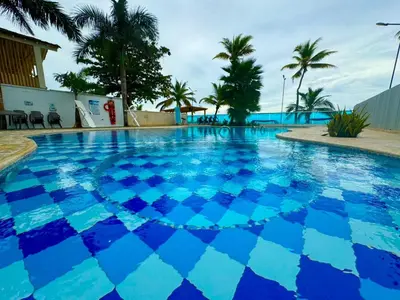 a large blue swimming pool with palm trees in the background at Apartamento de lujo frente al mar in Coveñas