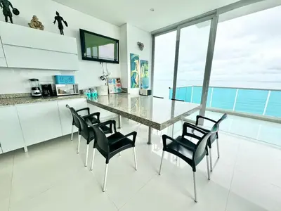 a kitchen with a large glass table and black chairs at Apartamento de lujo frente al mar in Coveñas