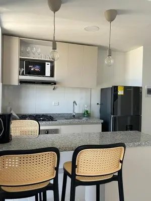 a kitchen with a counter with chairs and a refrigerator at Modern Apartment in Barranquilla in Barranquilla