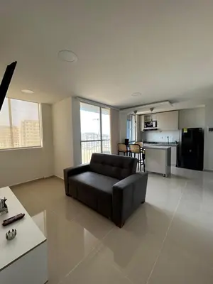 a living room with a black couch and a kitchen at Modern Apartment in Barranquilla in Barranquilla
