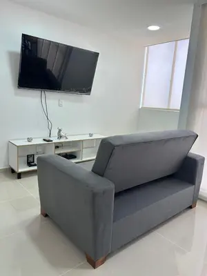 a gray couch in a living room with a flat screen tv at Modern Apartment in Barranquilla in Barranquilla