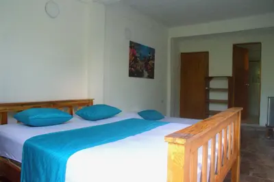 a bedroom with a large bed with blue pillows at MANGO BREEZE Casa de Playa en Tierrabomba in Tierra Bomba