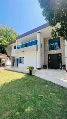 a large white building with a grass yard in front of it at Casa a 2 minutos de la playa en playa mendoza in Tubará