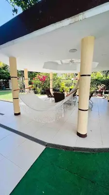a hammock on a patio with a green carpet at Casa a 2 minutos de la playa en playa mendoza in Tubará