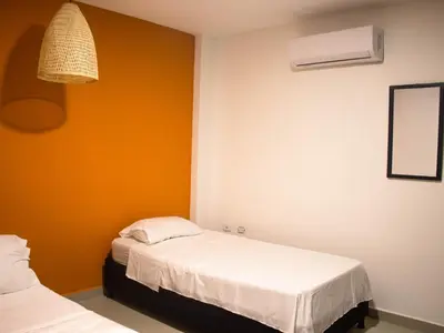 two beds in a room with an orange wall at Casa gimani Betts in Cartagena de Indias