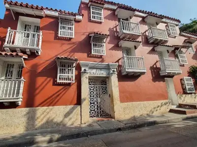 a red building with white windows and a door at Guesthouse Polar in Cartagena de Indias