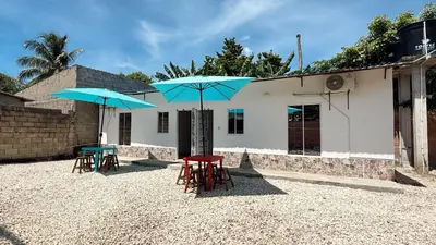 two tables and two blue umbrellas in front of a building at Cabaña Datalu 1 in Coveñas
