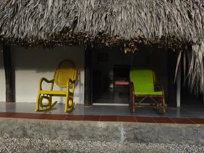 two yellow and green chairs sitting under a thatch roof at Glamping Tesoro Escondido in San Antero