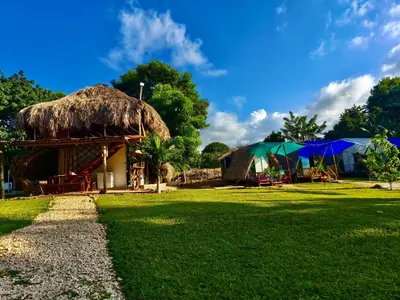 a hut with a grass roof with tables and umbrellas at Glamping Tesoro Escondido in San Antero