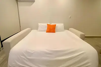 a white bed with an orange pillow on it at Lujoso apartamento con jacuzzi - Dominique in Cartagena de Indias