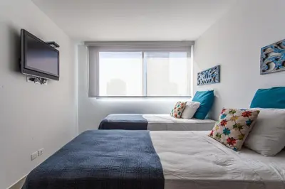 a bedroom with two beds and a flat screen tv at Lujoso Apto de 2 Hab en Piso 14 Morros City in Cartagena de Indias