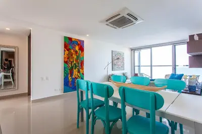 a dining room with a table and blue chairs at Lujoso Apto de 2 Hab en Piso 14 Morros City in Cartagena de Indias