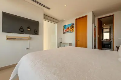 a bedroom with a large white bed and a flat screen tv at Condominio H2-Luxurious 2 BR / 16th F - Bocagrande in Cartagena de Indias