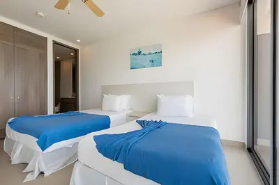 two beds in a white room with blue sheets at 1702 Morros City - Espectacular Apto en Bocagrande in Cartagena de Indias