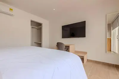 a bedroom with a white bed and a flat screen tv at Casa Encanto - Corazón de Getsemaní in Cartagena de Indias