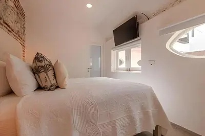 a white bedroom with a bed and a window at Casa Bóvedas - Paraíso de 5 habitaciones in Cartagena de Indias