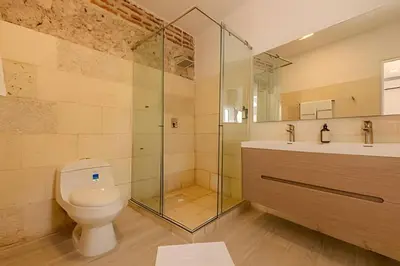 a bathroom with a toilet and a glass shower at Casa Bóvedas - Paraíso de 5 habitaciones in Cartagena de Indias