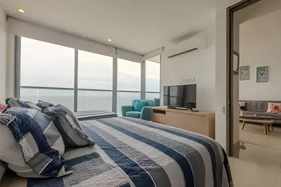 a bedroom with a bed and a tv and windows at Espectacular Vista al Mar en Morros City piso 19 in Cartagena de Indias