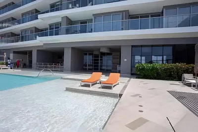 an apartment building with two chairs next to a swimming pool at Lujoso Apto de 2 Hab en piso 20 - Morros City in Cartagena de Indias