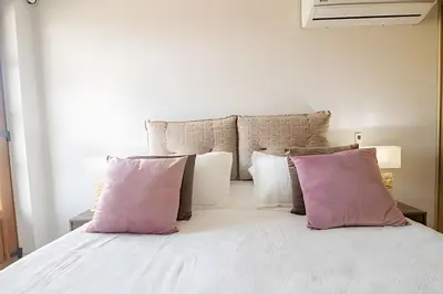 a white bed with pink pillows in a bedroom at Espectacular Vista al Castillo de San Felipe! in Cartagena de Indias