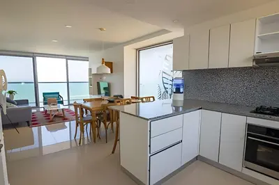 a kitchen with white cabinets and a dining room at Hermoso Apto Frente al Mar - Morros City piso 9 in Cartagena de Indias
