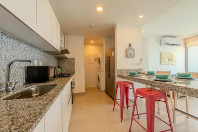 a kitchen with a sink and two red bar stools at 2102 Morros City - Espectacular Vista al Mar in Cartagena de Indias