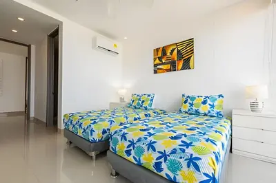 a white bedroom with a bed with blue and yellow sheets at Hermoso Apto Frente al Mar - Morros City 801 in Cartagena de Indias