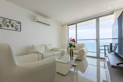 a living room with white furniture and a large window at Hermoso Apto Frente al Mar - Morros City 801 in Cartagena de Indias