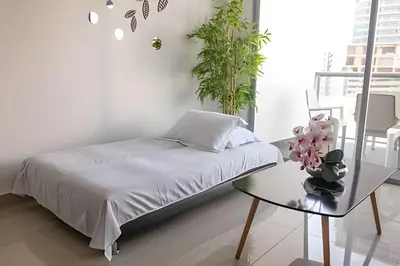 a bedroom with a bed and a table with a plant at Lujoso Apto de 1 Hab en Piso 7 - Infinitum in Cartagena de Indias